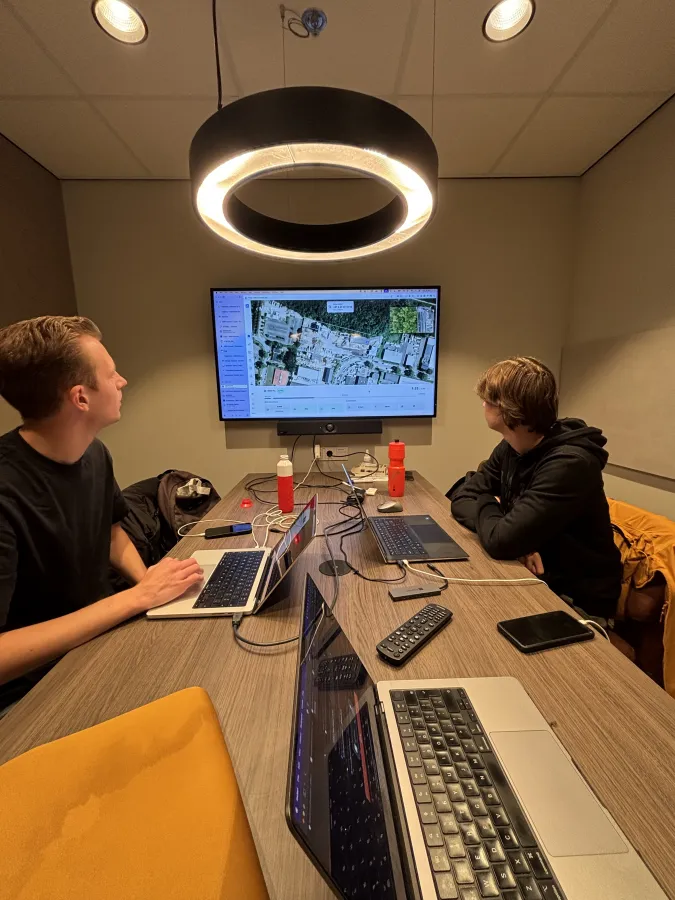 Twee collega's bekijken samen een dronekaart op het scherm in de vergaderruimte