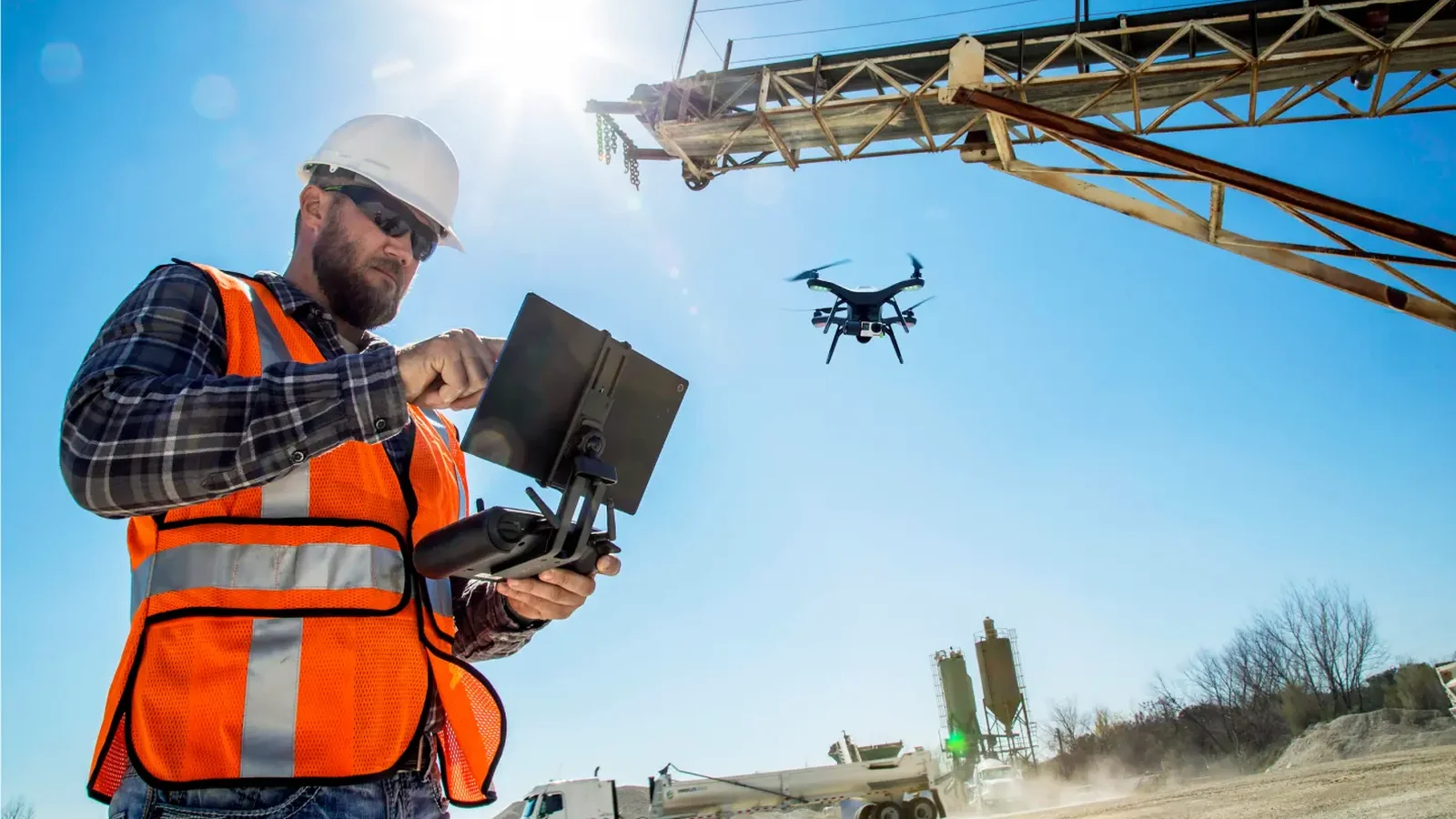 Medewerker in hi-vis bedient de drone met een tablet op een bedrijfsterrein